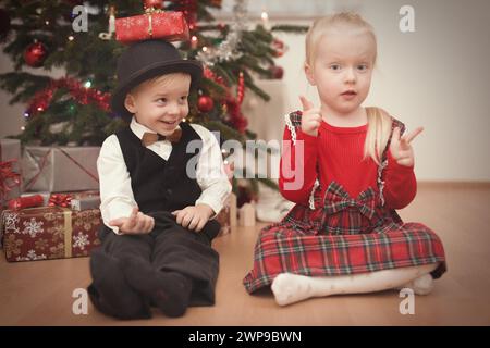 Kinder zum weihnachtsfeiertag packen Geschenke in der Nähe eines Baumes aus Stockfoto