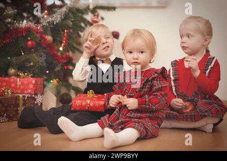 Kinder zum weihnachtsfeiertag packen Geschenke in der Nähe eines Baumes aus Stockfoto