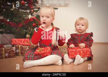 Kinder zum weihnachtsfeiertag packen Geschenke in der Nähe eines Baumes aus Stockfoto