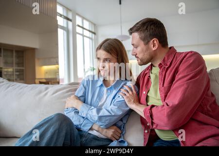 Uneinigkeit in Familienbeziehungen tausendjähriges Paar, entschuldigender Ehemann umarmt beleidigte Frau zu Hause. Stockfoto