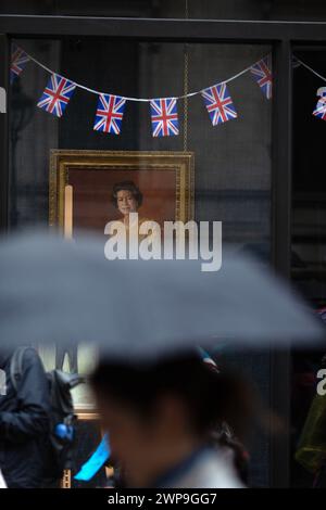 Porträts von König Karl III. Und der verstorbenen Königin Elisabeth II. Werden in einem Schaufenster gesehen, während sich die Menschen versammeln, um die Krönung des Königs in London zu sehen. Stockfoto