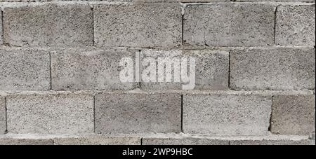 Wand aus unebenen grauen Zementblöcken. Betonzaun oder -Struktur. Die Beschaffenheit des Steins. Loses, loses Material. Kostengünstiger Dorfbau Stockfoto