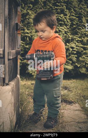 Kleiner Junge, der als Handwerker im Garten spielt, an schönen Herbsttagen Stockfoto