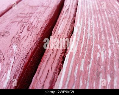 Holzstruktur. Holzbank in Burgunderrot mit Ölfarbe bemalt. Risse auf dem Baumstamm. Das Produkt der Boards. Feuchtigkeit auf Holz Stockfoto