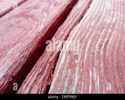 Holzstruktur. Holzbank in Burgunderrot mit Ölfarbe bemalt. Risse auf dem Baumstamm. Das Produkt der Boards. Feuchtigkeit auf Holz Stockfoto