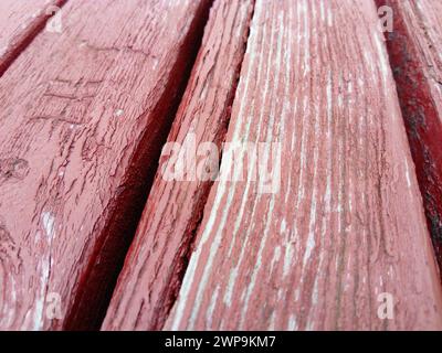Holzstruktur. Holzbank in Burgunderrot mit Ölfarbe bemalt. Risse auf dem Baumstamm. Das Produkt der Boards. Feuchtigkeit auf Holz Stockfoto