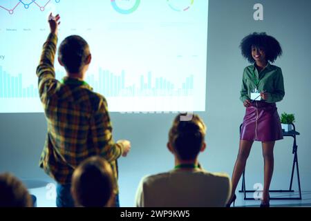 Selbstbewusste afroamerikanische Frau, Expertin mit Ständen vor Publikum, Vortrag und Beantwortung von Fragen im Konferenzraum. Stockfoto