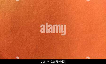 Ein Blatt dickes Papier von hellorangefarbener Farbe. Nahaufnahme. Intensiver Hintergrund. Natürliche seitliche Beleuchtung. Feine Pappe oder Papierstruktur. Licht Stockfoto