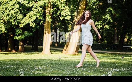 Fröhliche Frau, die barfuß im Stadtpark läuft Stockfoto
