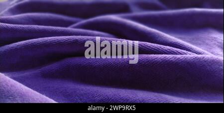 Blauer, zerknitterter Samt. Blau-violetter Samtstoff, wunderschön in Wellen gelegt. Weichzeichner. Stockfoto