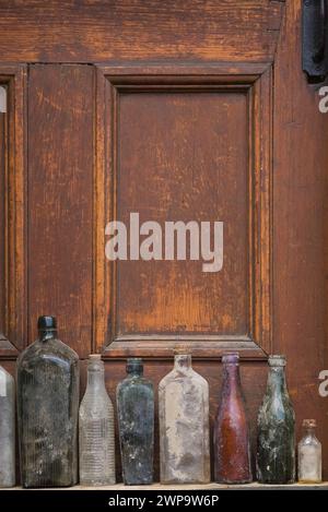 Nahaufnahme alter ausgegrabener Glasflaschen vor einem hölzernen Türhintergrund. Stockfoto