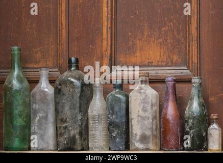 Nahaufnahme alter ausgegrabener Glasflaschen vor einem hölzernen Türhintergrund. Stockfoto