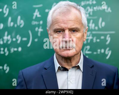 Frustrierter Oberlehrer, der vor einem Kreidetafel steht. Stockfoto