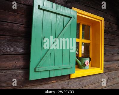 Ethno-Folk Holzläden an einem Fenster mit Holzrahmen, grün und gelb lackiert. Altes serbisches Haus, außen. Architektonischer Komplex Stanisici Stockfoto