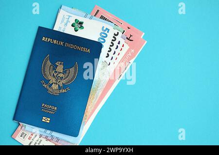 Blauer Indonesien Pass mit Geld und Flugtickets auf blauem Hintergrund Nahaufnahme. Tourismus und Reisekonzept Stockfoto