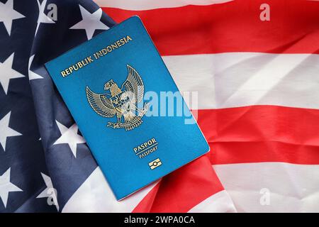 Pass der blauen Republik Indonesien auf dem Hintergrund der Nationalflagge der Vereinigten Staaten aus nächster Nähe. Tourismus und Diplomatie Stockfoto