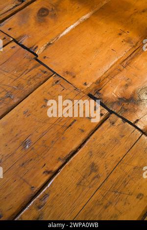 Alte zerkratzte und abgenutzte lackierte Kiefernholzdielen vom Fußgängerverkehr in einem alten Haus um 1760. Stockfoto