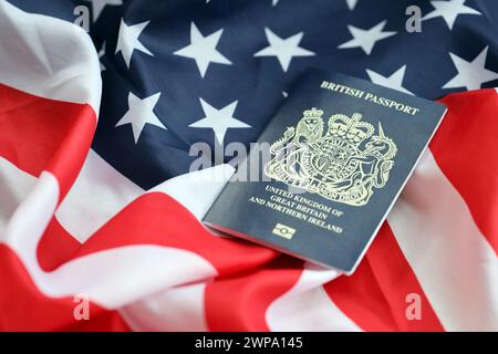 Blauer britischer Pass auf dem Hintergrund der US-Nationalflagge aus nächster Nähe. Tourismus und Diplomatie Stockfoto