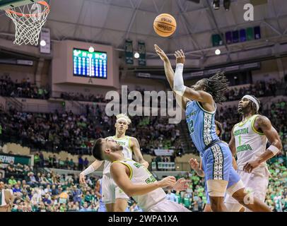 Tampa, Florida, USA. März 2024. Der Tulane Green Wave Guard KOLBY KING (12) macht sich im Yuengling Center in Tampa, Florida, für einen Layup über die University of South Florida Bulls JOSE PLACER (2) während des NCAA-Basketballspiels zwischen den Tulane Green Wave und der University of South Florida Bulls. (Kreditbild: © Israel Anta via ZUMA Press Wire) NUR REDAKTIONELLE VERWENDUNG! Nicht für kommerzielle ZWECKE! Stockfoto