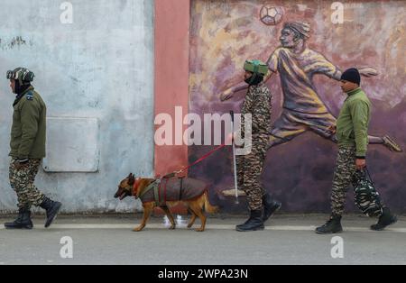 Srinagar, Indien. März 2024. Indische paramilitärische Truppen patrouillieren zusammen mit einem Schnüfferhund in der Nähe des Veranstaltungsorts, an dem der indische Premierminister Narendra Modi am 7. März eine öffentliche Kundgebung halten soll. Vor dem ersten Besuch des indischen Premierministers Narendra Modi im Tal seit der Aufhebung des Artikels 370 im Jahr 2019 sind Sicherheitsbeamte im Kaschmir-Tal auf der Hut, wodurch der besondere halbautonome Status der Region beendet wird. Quelle: SOPA Images Limited/Alamy Live News Stockfoto