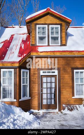 Holzdielen verkleidete Erweiterung auf einem alten zweistöckigen Haus aus dem Jahr 1826 mit rotem Blechdach im Winter. Stockfoto