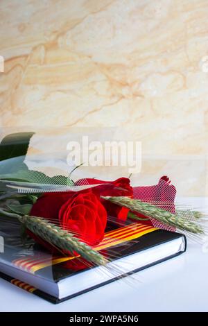 Sant Jordi Rosen auf einem Buch mit schwarzen Deckeln mit einem Band der Flagge Kataloniens Stockfoto