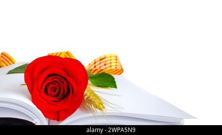 Rose von Sant Jordi auf einem offenen Buch mit leeren Seiten, mit einem Weizenohr und einem Band der katalanischen Flagge. Tag buchen Stockfoto