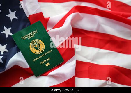 Grüner nigerianischer Pass auf dem Hintergrund der US-Nationalflagge aus nächster Nähe. Tourismus und Diplomatie Stockfoto