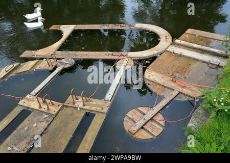 28/05/14 die Bretter werden im Dorfteich eingeweicht, bevor sie mit Lehm versehen werden. Mit Ton beschichtete Holzbretter sind mit Zehntausenden dekoriert Stockfoto