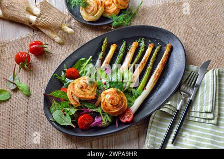 Gebratener grüner und weißer Spargel mit mediterranen Blattsalaten und warmen Teiglachsspiralen Stockfoto