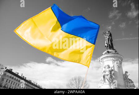 Ukrainische Flagge winkt auf dem Place de la Republique gegen Putins Krieg und zur Unterstützung der Ukraine. Paris, Frankreich. Hope-Konzept. Schwarz-weißer Hintergrund. Stockfoto