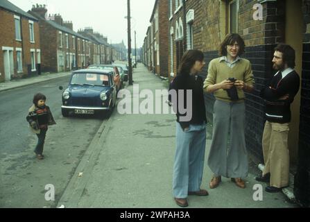 Britische modische junge Erwachsene Fischer aus den 1980er Jahren, arbeitslos und in der Eton Street herumhängen. Sie tragen Fackeln, die sehr beliebt waren - je breiter, desto besser. Der richtige Name für diesen Hosenstil ist Oxford Bags. Die Eton Street lag im Stadtgebiet Hessle Road und war eine traditionelle Arbeiterenklave und Heimat von Fischern und Hafenarbeitern. Hull, Humberside, England 1980 HOMER SYKES Stockfoto