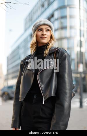 Cooles modisches Street Girl in trendiger Black Rock Kleidung mit Hut, Lederjacke, Pullover und Hose Spaziergänge in der Stadt. Outfit Im Urbanen Damenlook Stockfoto