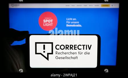 Handyhalter mit Logo von Correctiv - Recherchen für die Gesellschaft gGmbH vor der Webseite. Schwerpunkt auf dem Display des Telefons. Stockfoto