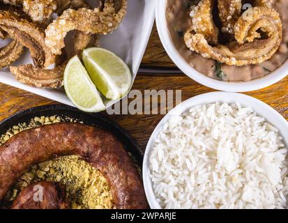 Typischer Esstisch im Inneren Brasiliens. Schweinefleisch, Bohnen, Bohnen-Tutu, Schweineschalen, Reis und Farofa. Bergbauernahrung, zuhause hergestellt. Aromen von Brasilien. Stockfoto