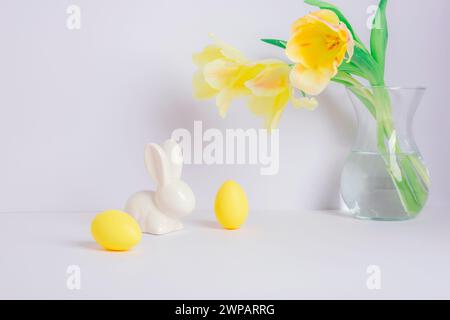 Gelbe Tulpen in Vase und Osterdekoration auf weißem Hintergrund. Osterkonzept. Stockfoto