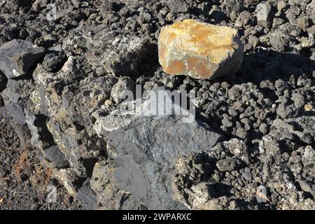 Farben Kontrast eines Vulkanfelsens Schwefel- und eisenfarben und die bleiblaue Farbe des Basaltgrundes auf dem Hintergrund, Ätna Park, Sizilien, Italien Stockfoto