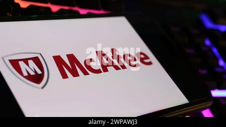 Viersen, Deutschland - 9. Februar. 2024: Nahaufnahme des Smartphones mit Logo-Schriftzug der Firma McAfee auf der Computertastatur Stockfoto