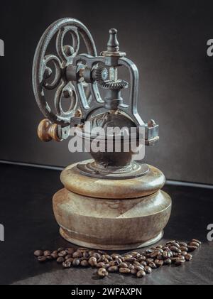 Alte originale Kaffeebohne Original Mühle Metall Shake Wheel mit Handkurbel und Kaffeebohnen auf dunklem Hintergrund. Antike Kaffeemühle mit Spuren von Stockfoto