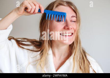 Mädchen versteckt sich hinter einer Haarbürste. Haarpflegekonzept. Stockfoto