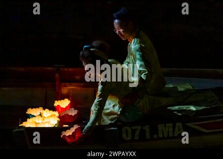 Ein Paar, das schwimmende Kerzen auf dem Fluss Thu Bon in Hoi, einer antiken Stadt, in Vietnam, abwirft. Eine alte Tradition. Stockfoto