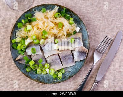 In Scheiben geschnittener Hering serviert mit Sauerkraut Stockfoto