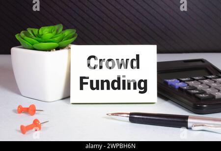Crowdfunding, Eine goldene Sparkasse, Karte und Taschenrechner auf Holzhintergrund mit Text Crowdfunding Stockfoto