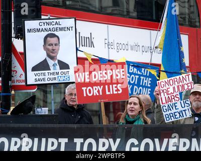 Demonstranten schwenkten am Haushaltstag 6. März 2024 vor dem Londoner Westminster-Parlament Banner und Plakate mit Anti-Tory- und Anti-Brexit-Slogans Stockfoto