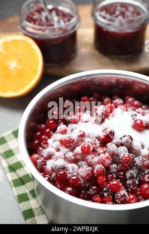 Preiselbeersauce herstellen. Frische Preiselbeeren mit Zucker in einem Topf auf dem Tisch, Nahaufnahme Stockfoto