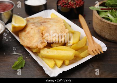 Leckerer Fisch und Chips serviert auf Holztisch, Nahaufnahme Stockfoto