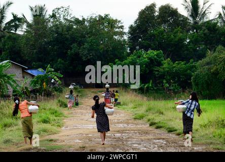 Junge arkanesische Mädchen, die Wasserkrüge in ihr Dorf in Mrauk-U im Staat Rakhine, Myanmar, tragen. Stockfoto