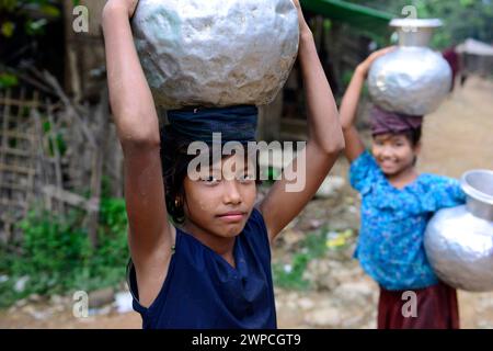 Junge arkanesische Mädchen, die Wasserkrüge in ihr Dorf in Mrauk-U im Staat Rakhine, Myanmar, tragen. Stockfoto