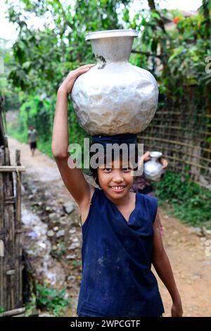 Junge arkanesische Mädchen, die Wasserkrüge in ihr Dorf in Mrauk-U im Staat Rakhine, Myanmar, tragen. Stockfoto