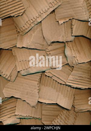 Textur aus zerrissenen Pappstücken. Brauner Kartonhintergrund. Recyclingkonzept. Grobe Stücke aus geriffeltem braunem Wellpappe Stockfoto